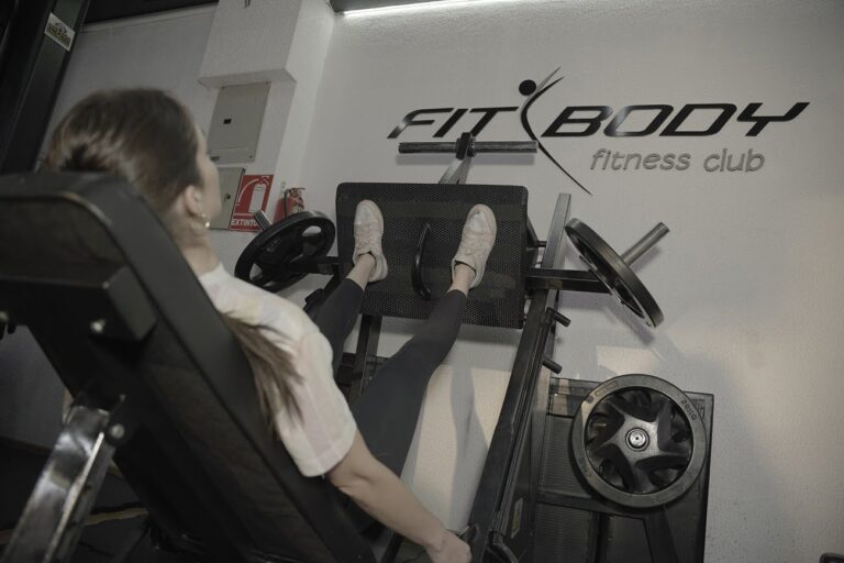 chica realizando piernas con maquina en gimnasio fitbody